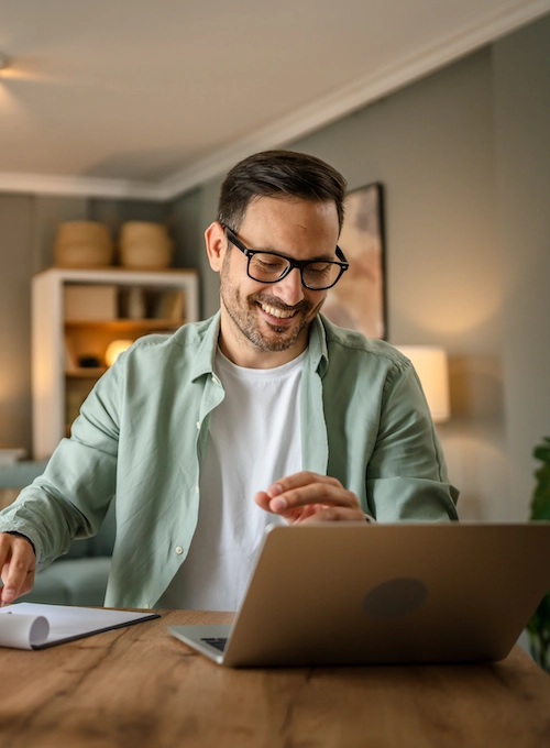 man happily working at home on their laptop